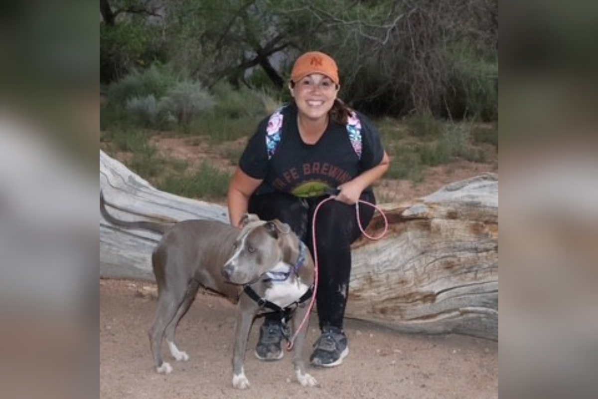 Sandoval County Animal Care Services volunteer Jessica Clark sits next to a blue-nose pit bull cross.