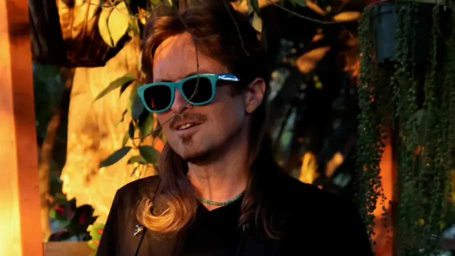 A man wearing sunglasses holds a guitar