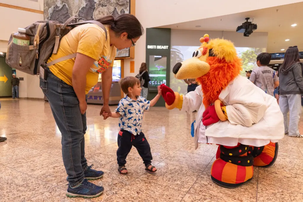 A baseball mascot named Orbit shakes hands with a small child