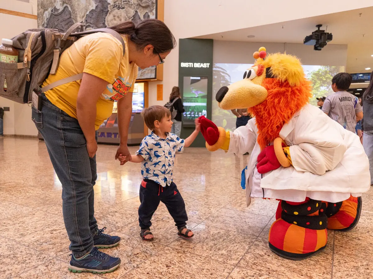 A baseball mascot named Orbit shakes hands with a small child