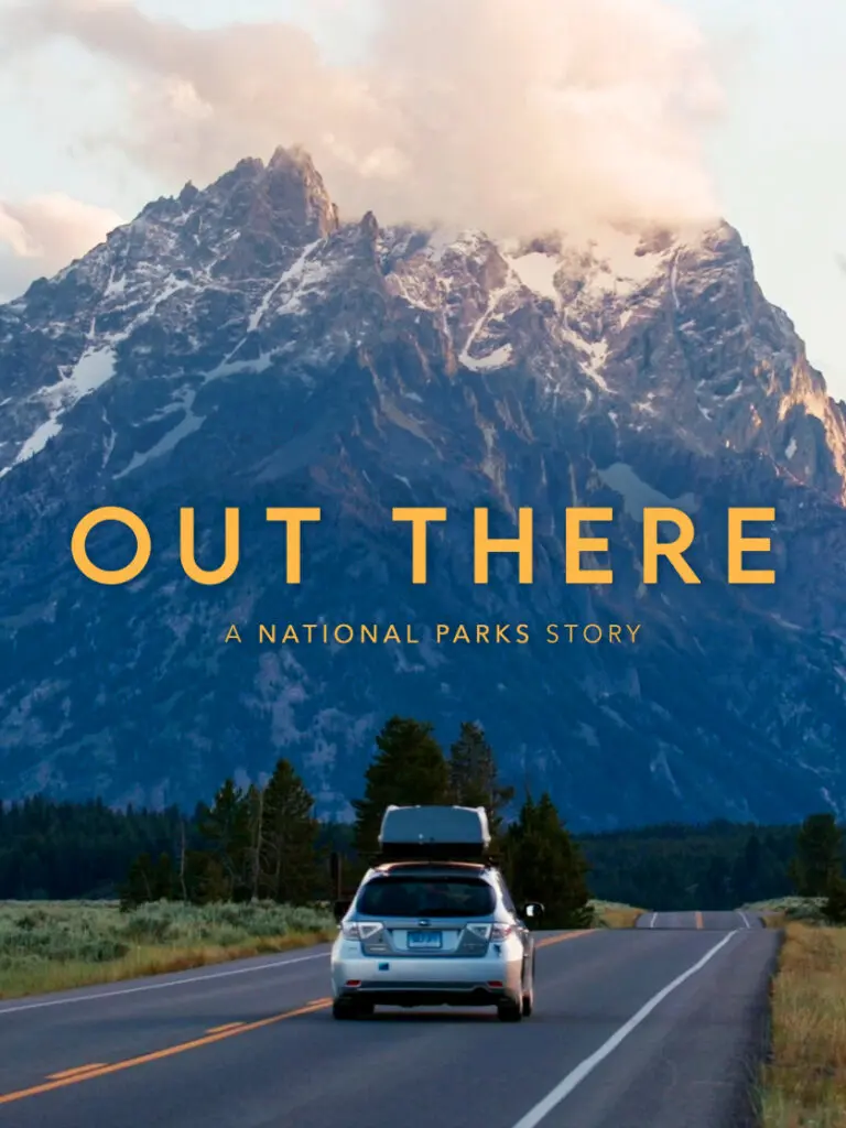 A car loaded with luggage drives toward a mountain peak
