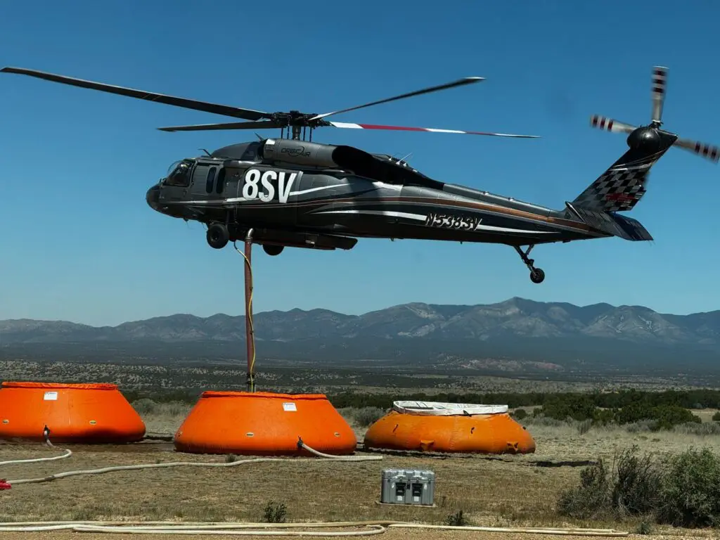A helicopter prepares to load water for fire suppression on the Deer Canyon Fire in Torrance County (NMFD, Jun., 2026)