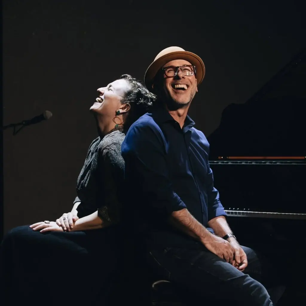 Two musicians, a man and a woman, stand back to back