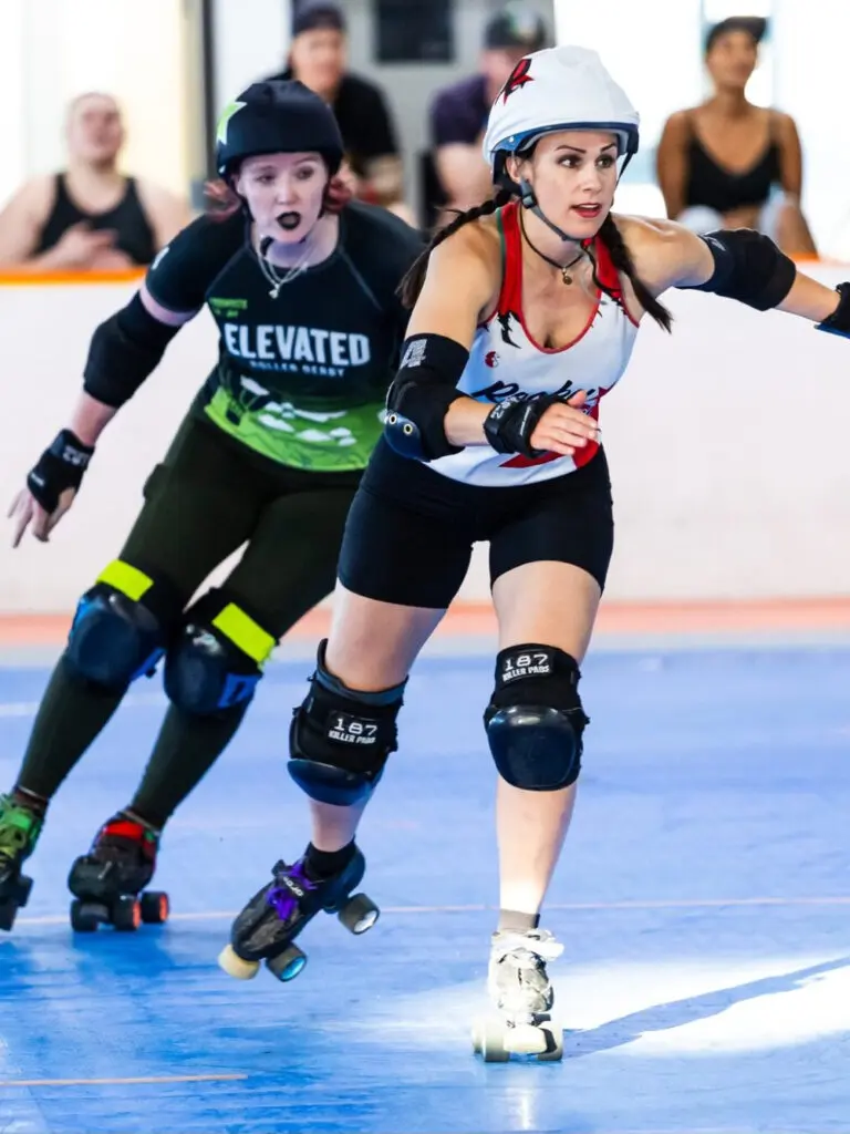 Two women on skates play in roller derby match.