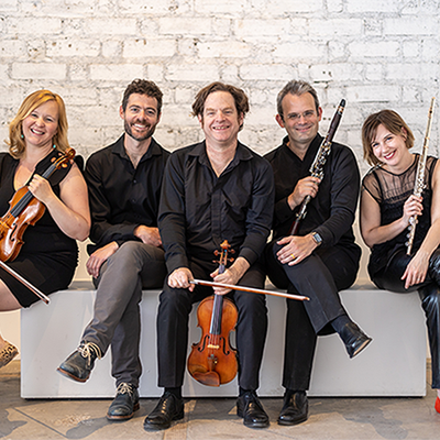 A classical quintet poses with their instruments on a bench.