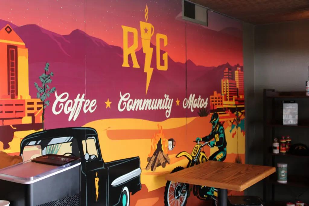 The wall of a coffee shop is painted with a mural of a pickup truck and a motorcycle.