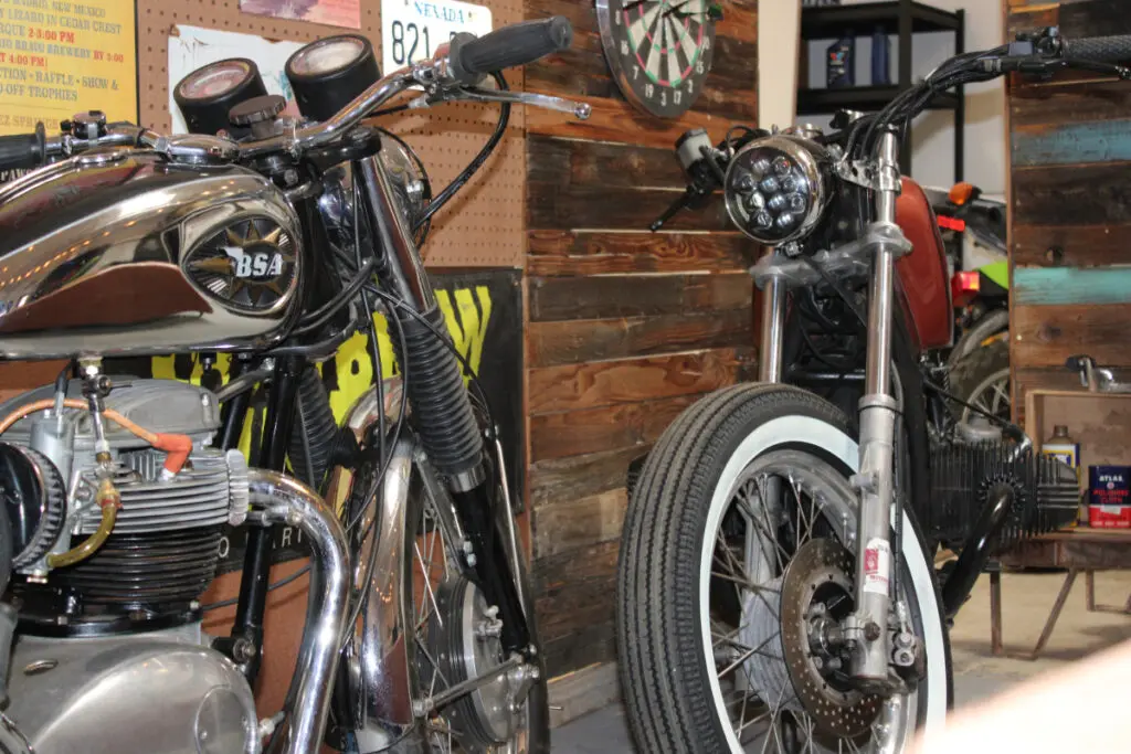 Two motorcycles lean against a shop wall.