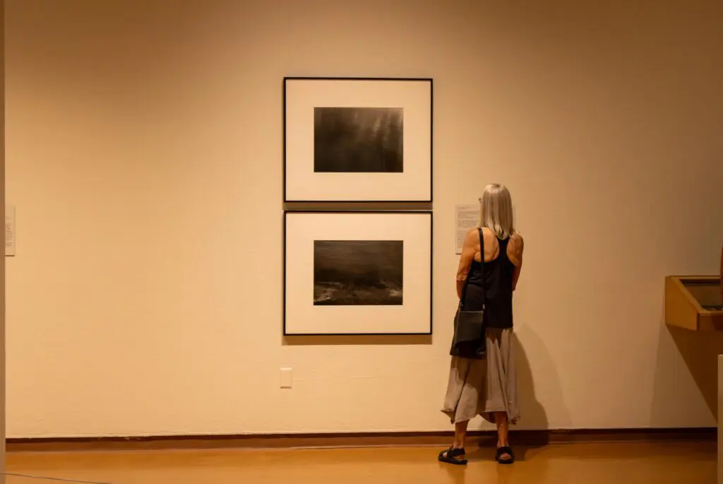 A person at the UNM Art Museum reading the art labels (Photo by Sara Atencio-Gonzales)