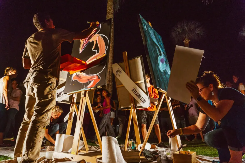 Several artists paint at easels on stage.