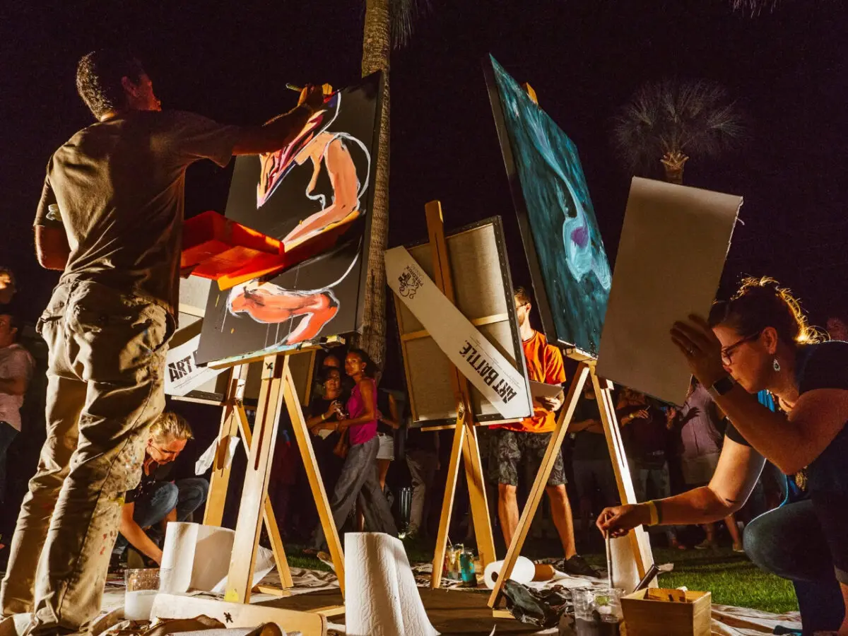 Several artists paint at easels on stage.