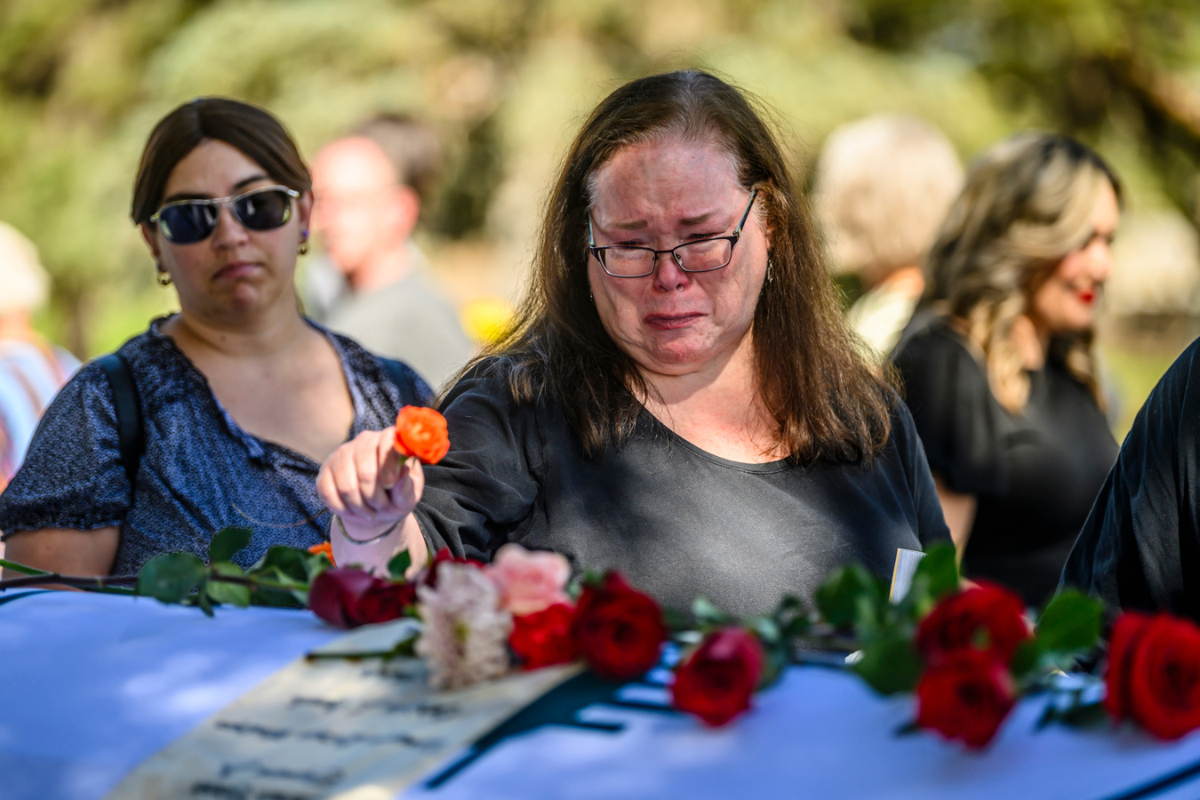 Angela Cantrell weeps as she places a flower on top of casket holding the remains of her brother Kenneth Allen Wofram during a memorial service for homeless folks who have died throughout the year. The event was held at Fairview Memorial Park Thursday morning. Photo by Roberto E. Rosales for the Paper