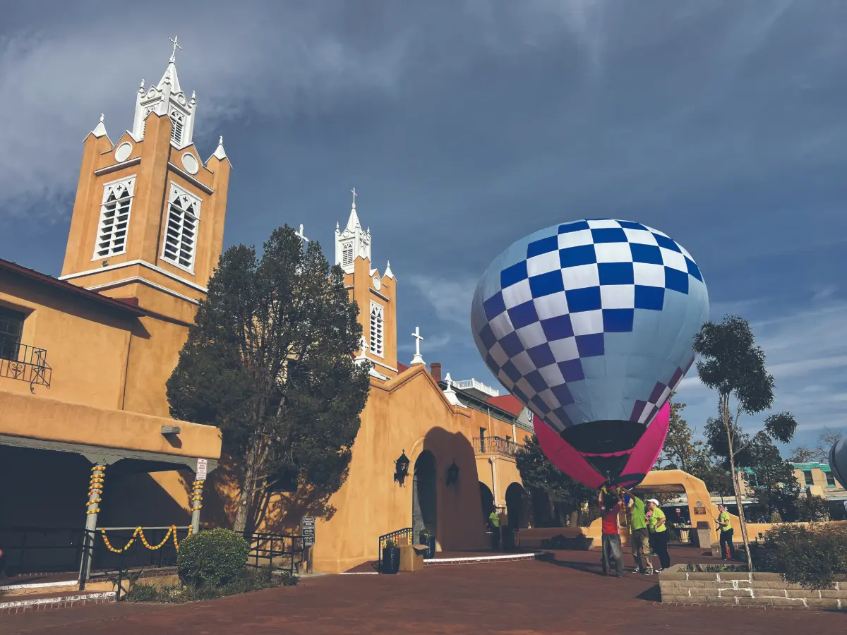 A hot air balloon inflates in front of an old church.