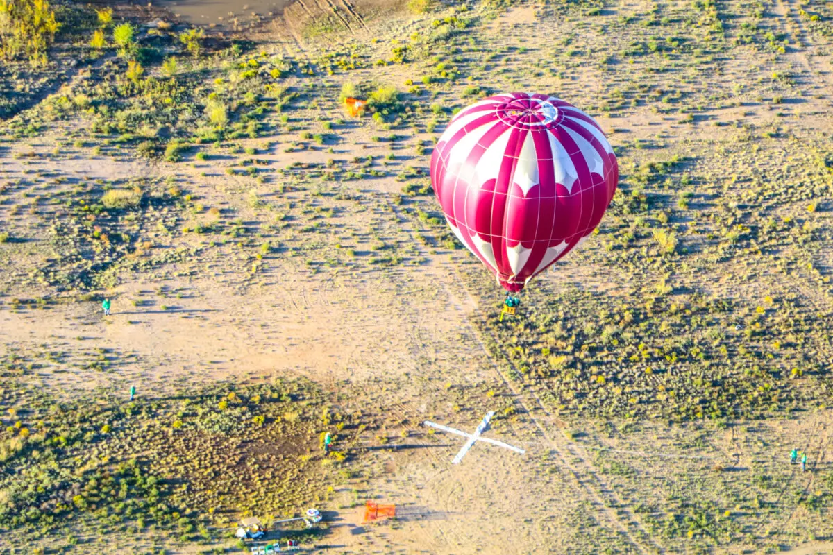 A hot air balloon landing on a giant white X. (Photo by Scott Hardy, Albuquerque International Balloon Fiesta)
