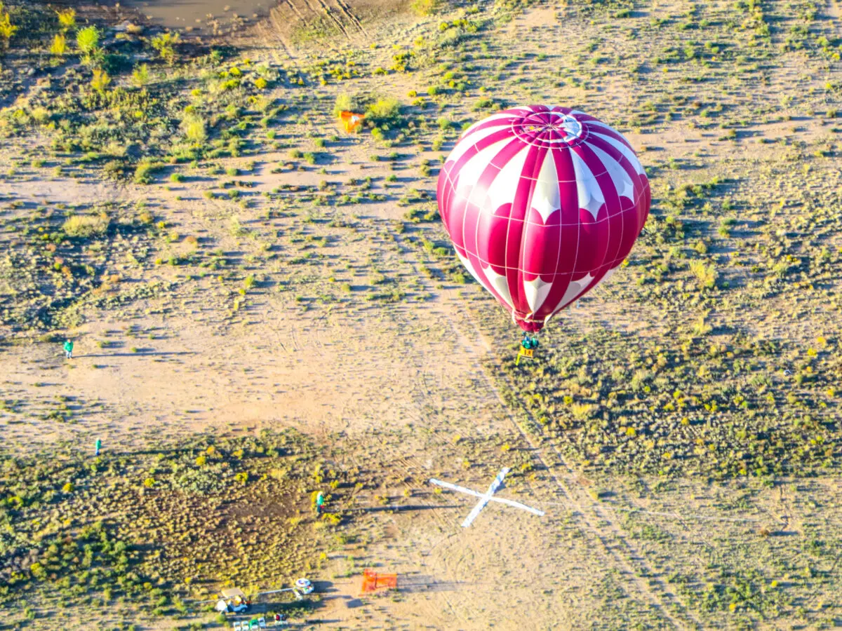 A hot air balloon landing on a giant white X. (Photo by Scott Hardy, Albuquerque International Balloon Fiesta)