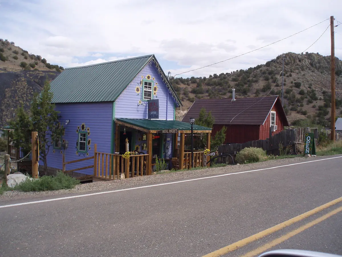 An old blue house sits along a rural highway.