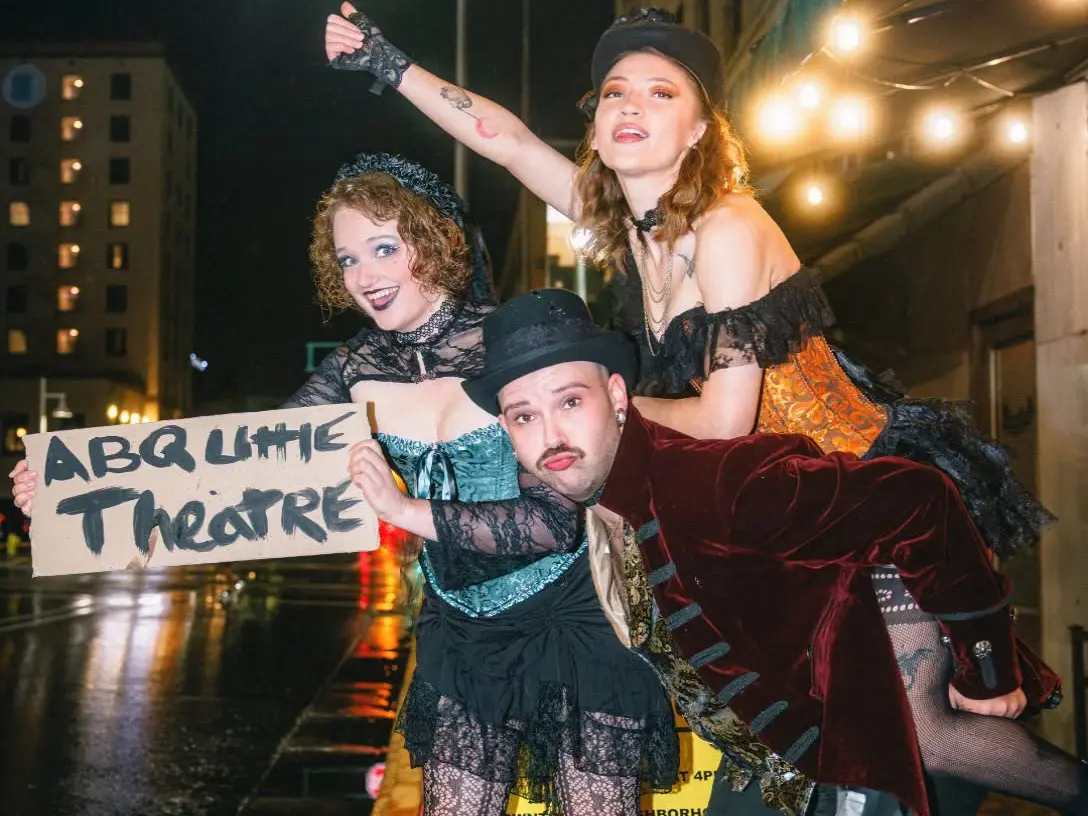 Three actors, dressed up for The Rocky Horror Show, pose on a street corner.