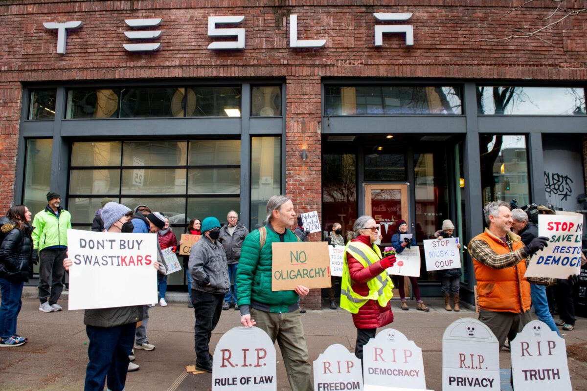 Demonstrators gather in opposition to Tesla and U.S. DOGE Service-related cuts by billionaire CEO Elon Musk in front of a dealership in Seattle on Feb. 13. Daniel Berman/For The Washington Post