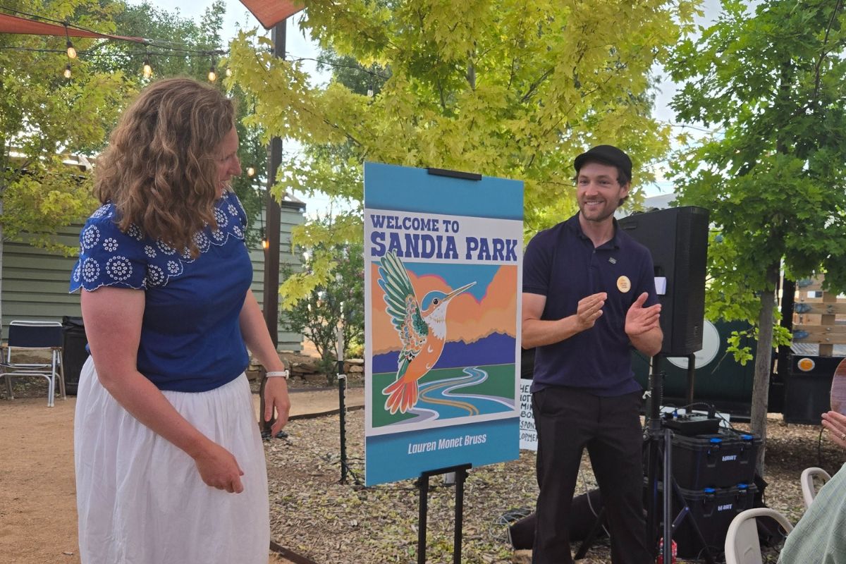 Bernalillo County Commissioner Chair Eric Olivas, right, and winning designer, Lauren Monet Bruss, unveil the winning proposed ‘Welcome to Sandia Park’ sign at the EMPAC community gathering on July 9th, held at Lantern Ridge. (EMPAC)
