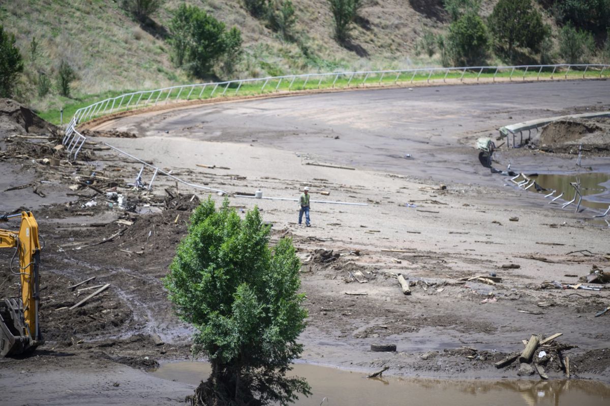 A man crosses the Ruidoso Downs Racetrack which was partially destroyed after the flood, Wednesday, July 9, 2025, in Ruidoso, N.M. (AP Photo/Roberto E. Rosales)